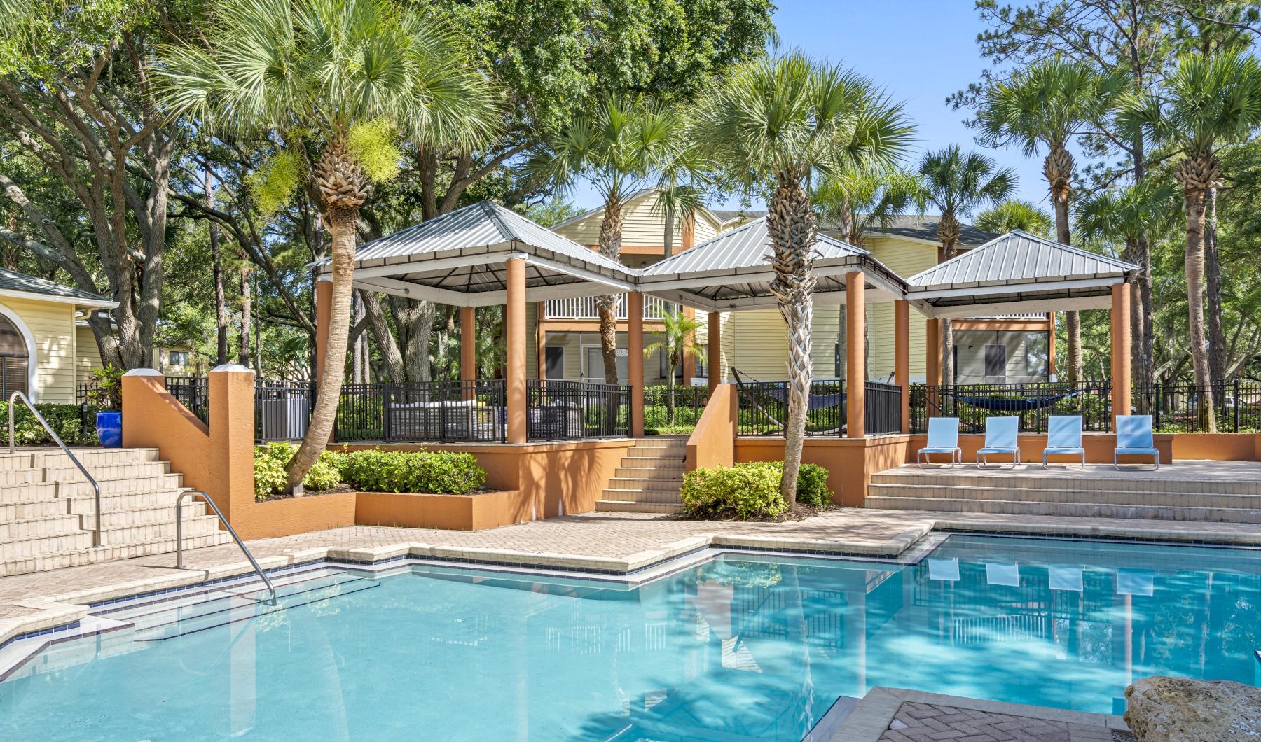 a pool with a gazebo and trees around it